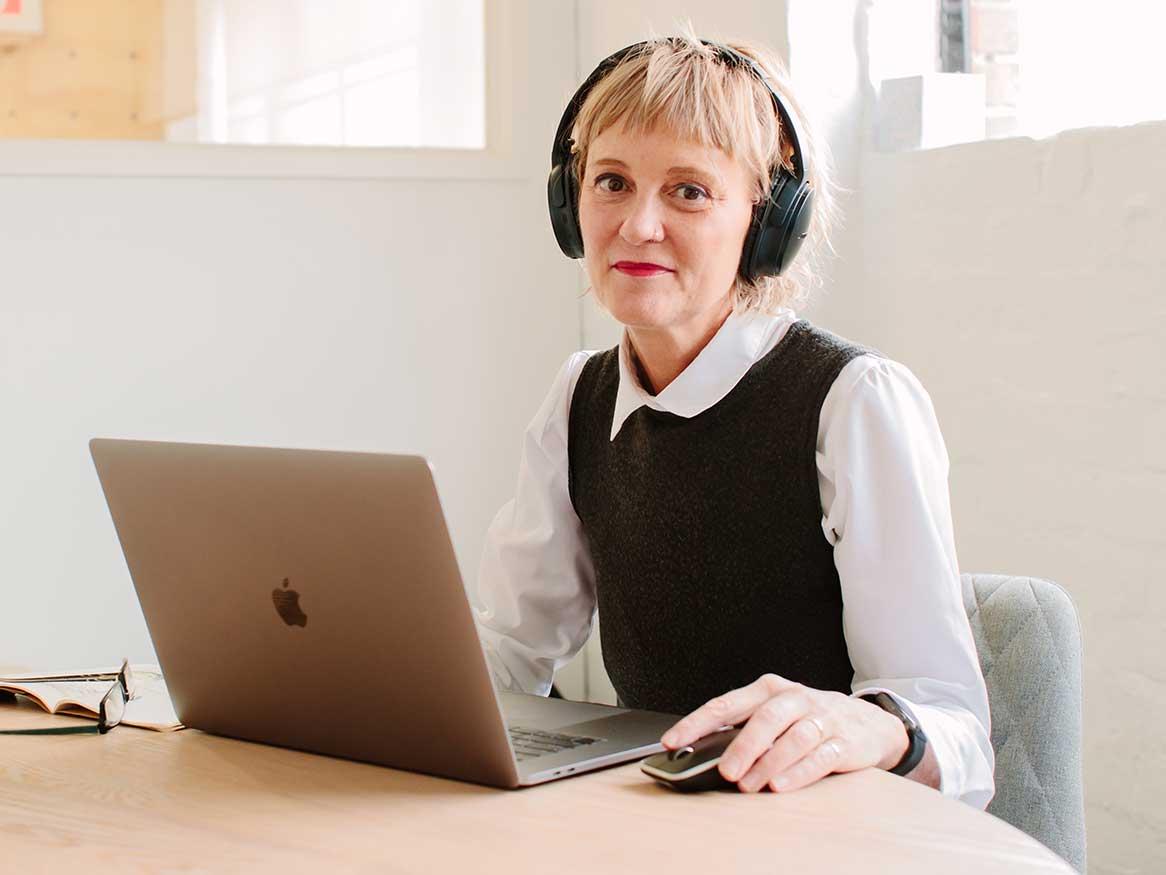 Female student with laptop, wearing headphones